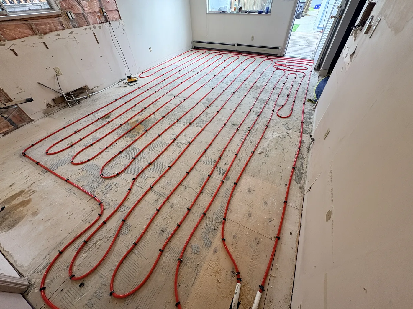 Hydronic radiant in-floor heating PEX tubing laid across a subfloor before pour